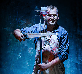 Image showing Bloody Halloween theme: crazy killer as butcher with saw