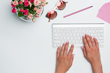 Image showing Office desk table with female hands, computer, supplies, flowers