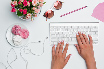 Image showing Office desk table with female hands, computer, supplies, flowers