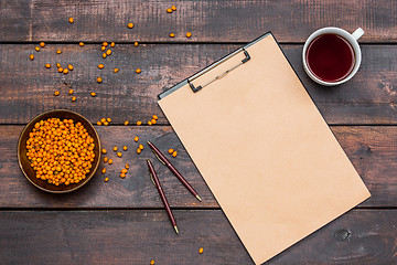 Image showing Office desk table with cup, notebook, fresh sea buckthorn berries on wooden table