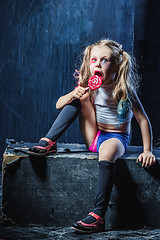 Image showing The funny crasy girl with candy on dark background