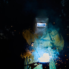 Image showing welder worker welding metal by electrode