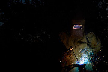 Image showing welder worker welding metal by electrode