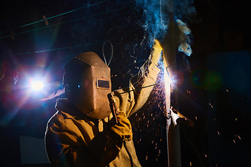 Image showing welder worker welding metal by electrode