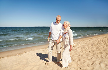 Image showing happy senior couple walking along summer beach