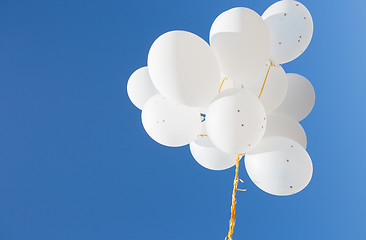 Image showing close up of white helium balloons in blue sky