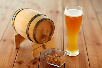 Image showing close up of beer glass, peanuts and wooden barrel