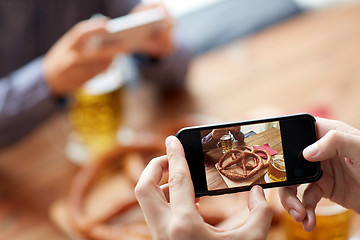 Image showing close up of hands picturing pretzel by smartphone