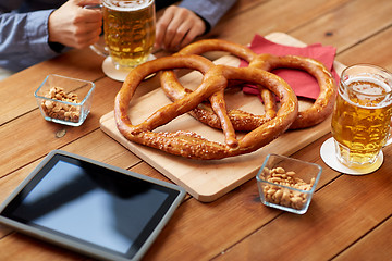 Image showing close up of man drinking beer with pretzels at pub