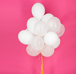 Image showing close up of white helium balloons over pink