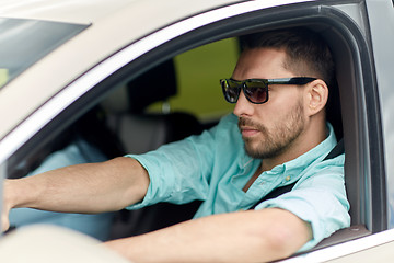 Image showing young man in sunglasses driving car