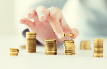 Image showing close up of female hand putting coins into columns