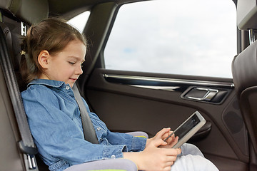 Image showing happy little girl with tablet pc driving in car