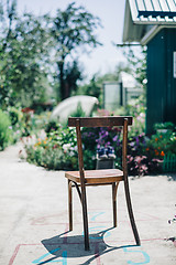 Image showing Old wooden chair on asphalt against of garden