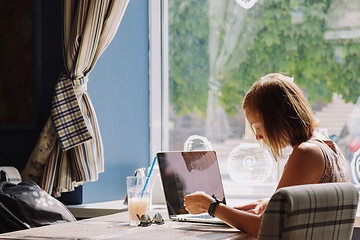 Image showing Young short-haired woman using laptop in cafe