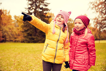 Image showing happy little girls pointing finger in autumn park