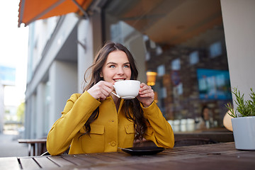 Image showing happy woman drinking cocoa at city street cafe