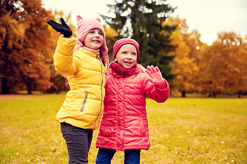 Image showing two happy little girls waving hand in autumn park