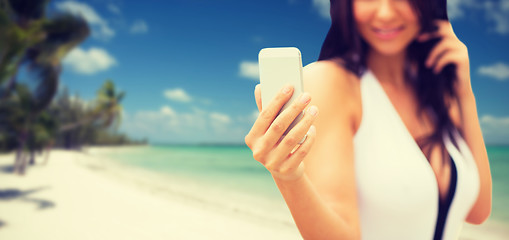 Image showing young woman taking selfie with smartphone on beach