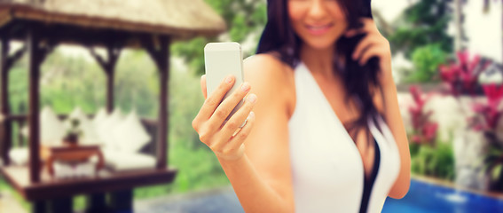 Image showing woman taking selfie with smartphone over bungalow