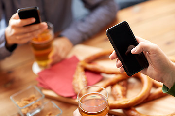 Image showing close up of hands with smartphones and beer at bar