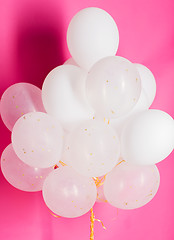 Image showing close up of white helium balloons over pink