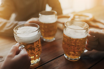 Image showing close up of hands with beer mugs at bar or pub