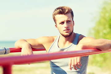 Image showing young man exercising on parallel bars outdoors