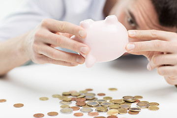 Image showing close up of man pouring coins from piggy bank