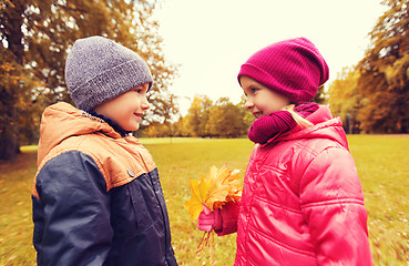 Image showing little boy giving autumn maple leaves to girl