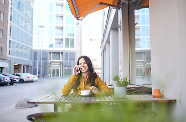 Image showing happy woman calling on smartphone at city cafe