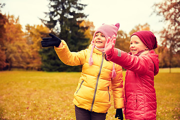 Image showing two happy little girls waving hand in autumn park