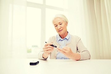 Image showing senior woman with glucometer checking blood sugar