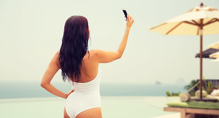 Image showing young woman taking selfie with smartphone on beach