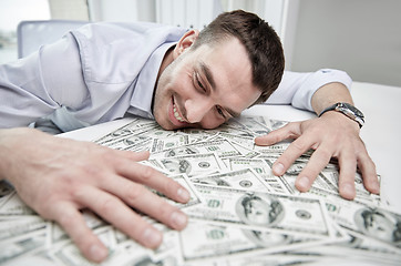 Image showing happy businessman with heap of money in office