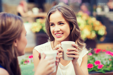 Image showing smiling young women with coffee cups at cafe