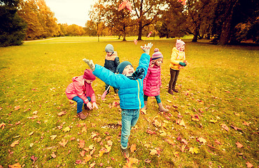 Image showing happy children playing with autumn leaves in park