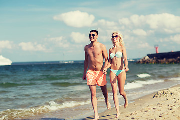 Image showing happy couple in swimwear running on summer beach