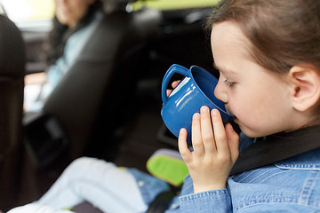 Image showing little girl driving in car and drinking from cup