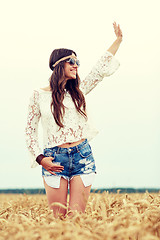 Image showing smiling hippie woman on cereal field waving hand