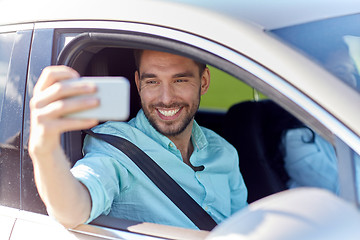 Image showing happy smiling man with smartphone driving in car