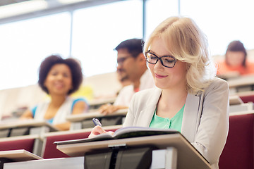 Image showing student girl writing to notebook in lecture hall