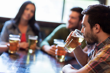 Image showing happy friends drinking beer at bar or pub