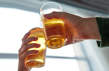 Image showing close up of hands clinking beer glasses at pub