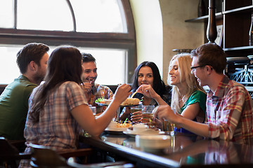 Image showing happy friends with beer eating at bar or pub