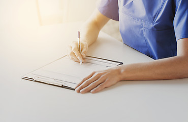 Image showing close up of doctor or nurse writing to clipboard