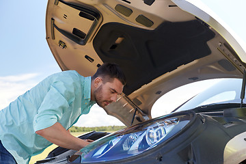 Image showing man with open hood of broken car at countryside