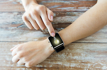 Image showing close up of hands with light bulb on smart watch