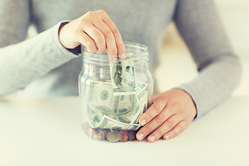 Image showing close up of woman hands and dollar money in jar