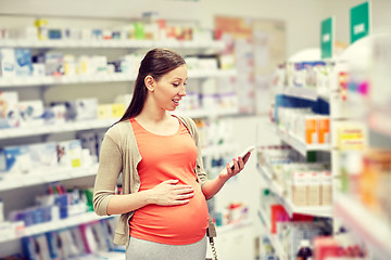 Image showing happy pregnant woman with smartphone at pharmacy